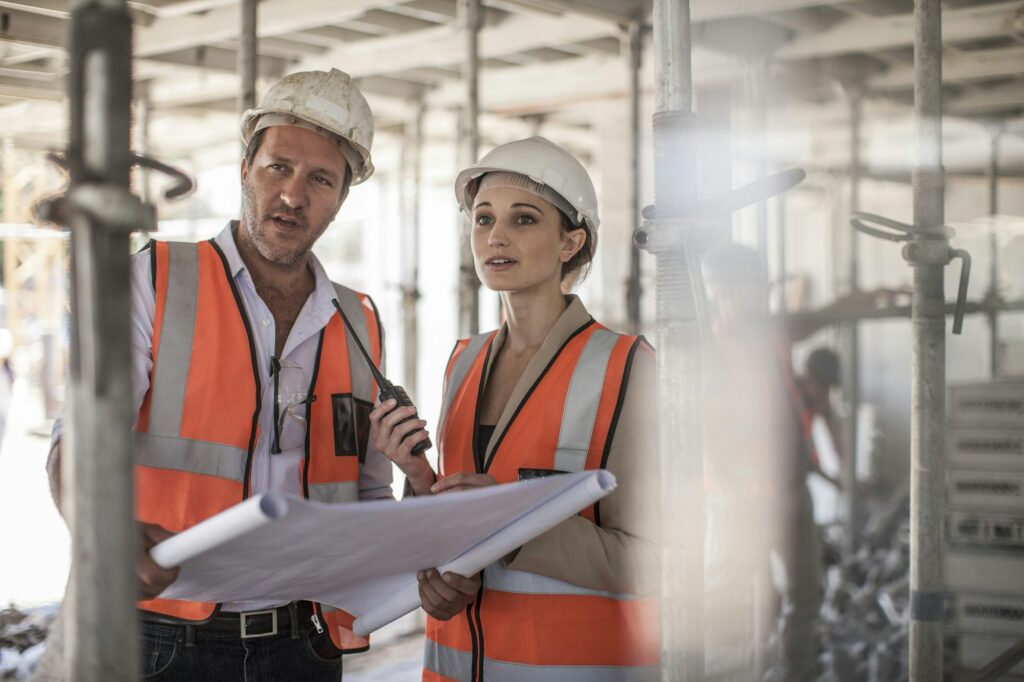 Female and male builders with blueprint on construction site